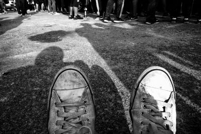 Low section of person wearing canvas shoes while standing on road