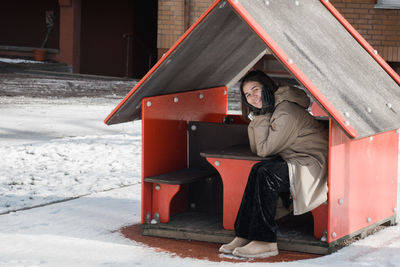 Woman sitting on snow covered road during winter