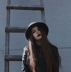 Portrait of young woman standing against wall