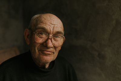 Close-up portrait of senior man against black background