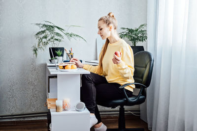 Freelancer young woman eating healthy food when working from home. woman eating healthy grain