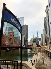 Bridge over river by buildings against sky in city