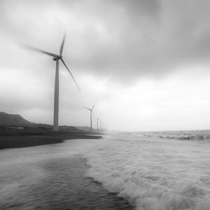 Wind turbines on sea shore against sky