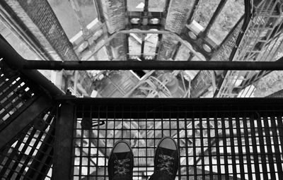 Low section of person standing on metal grate