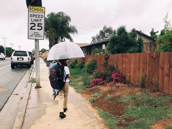 Full length of man walking on road in city during rainy season