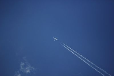 Low angle view of airplane flying against blue sky