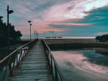 Bridge over street against sky during sunset