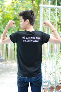 Rear view of man gesturing towards text on his t-shirt outdoors