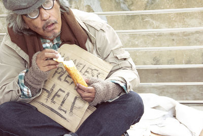 Man eating food while holding cardboard with text