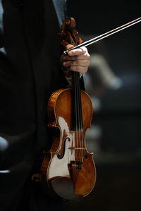 Cropped hand of man playing violin outdoors