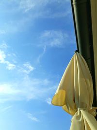 Low angle view of yellow umbrella against blue sky