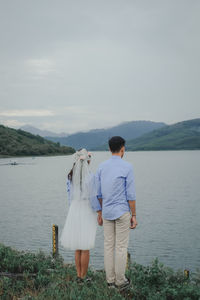 Rear view of couple standing on mountain against sky