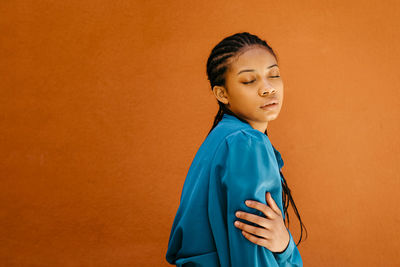 Mid adult woman standing against orange background
