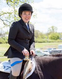 Portrait of smiling woman riding horse against sky