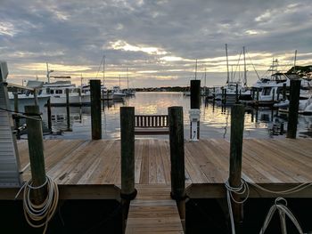 Wooden posts in sea against sky during sunset