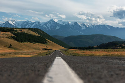 Road leading towards mountains against sky