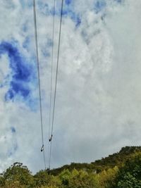 Low angle view of electricity pylon against cloudy sky