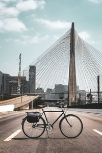 Bicycle parked on bridge against buildings in city against sky