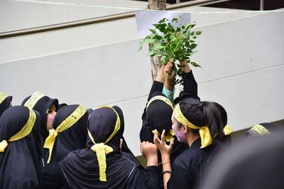 Rear view of people standing against plants