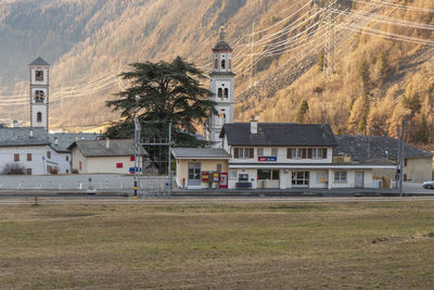 Houses on field by buildings against mountain