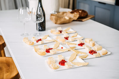 Preparing appetizers with wine for a gathering. unfocused hands arranging cheese and bread 