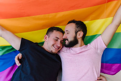 Two homosexual men holding lgbtq flag.