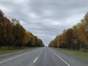 Road amidst trees against sky during autumn