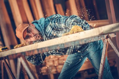 Male carpenter blowing sawdust on workbench