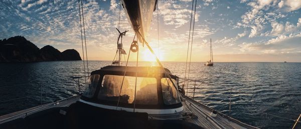 Sailboats in sea against sky during sunset