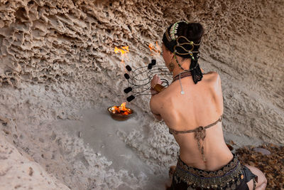 Rear view of woman with arms raised standing on beach