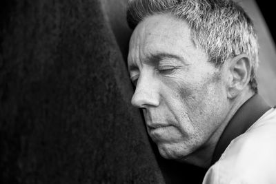 Close-up of man with eyes closed leaning on metal