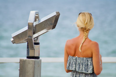 Rear view of woman standing by sea against sky