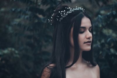 Beautiful young woman wearing tiara against plants