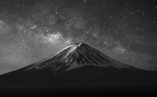 Scenic view of snowcapped mountains against star field at night