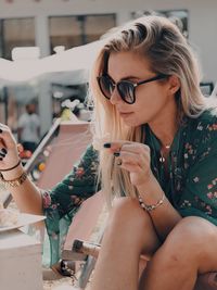 Midsection of woman with sunglasses sitting outdoors