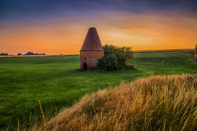 Built structure on field against sky during sunset