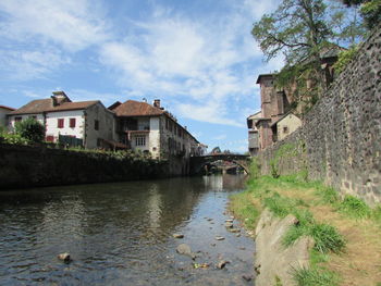 River amidst houses and buildings in town against sky