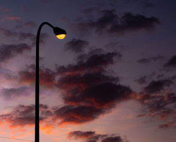 Low angle view of street lights against orange sky
