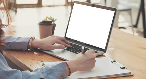 Midsection of woman using laptop on table