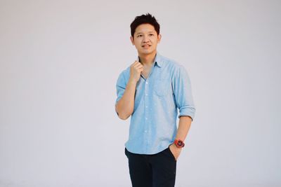 Portrait of young man standing against white background