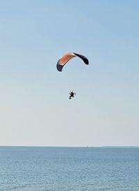 Low angle view of person paragliding against sea