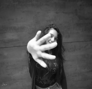 Portrait of a young woman standing against wall