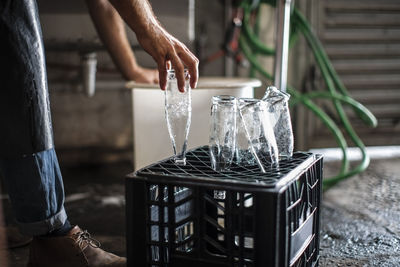 Man placing clean empty glass bottles on crate