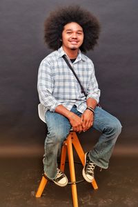 Man with curly hair smiling sitting in studio chair