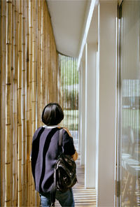 Rear view of woman standing by window