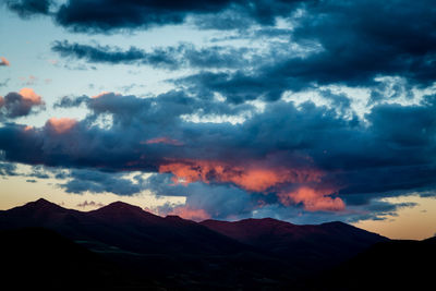 Scenic view of silhouette mountains against dramatic sky