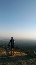 Full length of man with bicycle standing on landscape