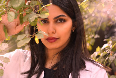 Portrait of young woman with eyes closed against plants