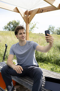 Young woman using mobile phone while sitting on chair