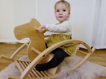 Portrait of cute baby sitting on a rocking horse at home